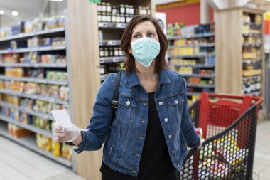 Süpermarkette tıbbi maskeli beyaz kadın.