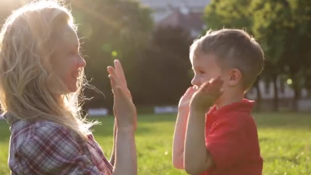 Mãe feliz e criança palmas mãos no pôr do sol — Vídeo de Stock