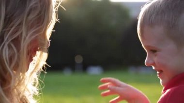 Mutlu gülümseyen anne ve çocuk günbatımı üzerinde oynamak