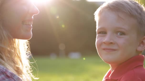 Abrazando feliz mamá y el juego del niño en la puesta del sol — Vídeo de stock