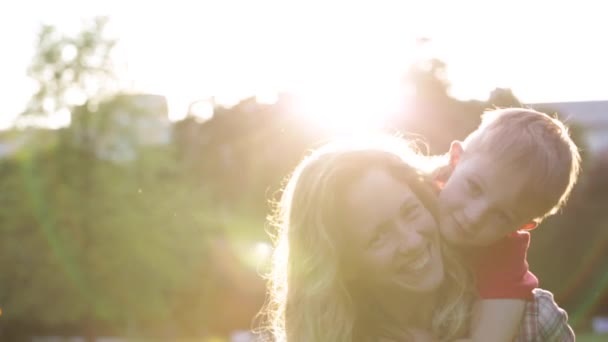 Feliz madre sonriente con el niño en la puesta del sol — Vídeos de Stock
