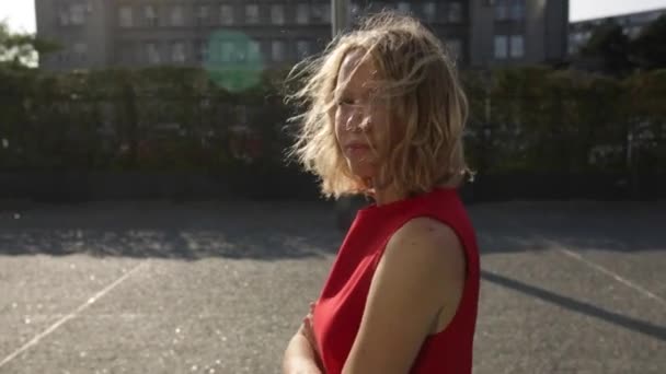 Giovane donna bella felice con i capelli ricci biondi sorridente alla macchina fotografica a piedi in città — Video Stock