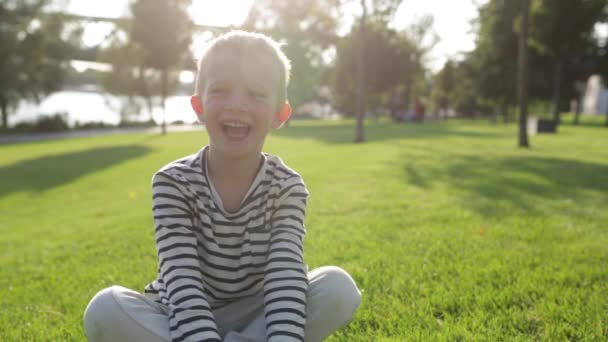 Lindo hermoso niño feliz sonriendo, sentado en la hierba — Vídeo de stock