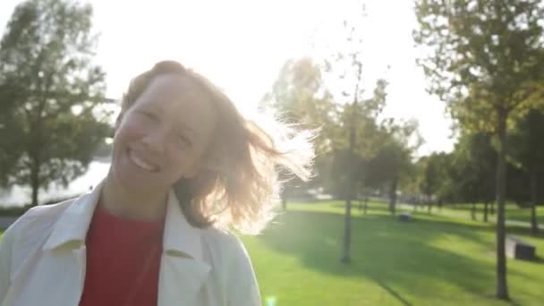 Jovem mulher bonita feliz com cabelo encaracolado loira sorrindo, vento soprando — Vídeo de Stock