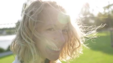 Genç mutlu güzel kadın sarışın kıvırcık saçlı gülümseyen, Rüzgar esiyor