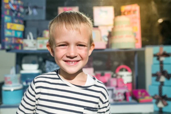 Cute beautiful happy little boy smiling in front of shopwindow — Stock Photo, Image