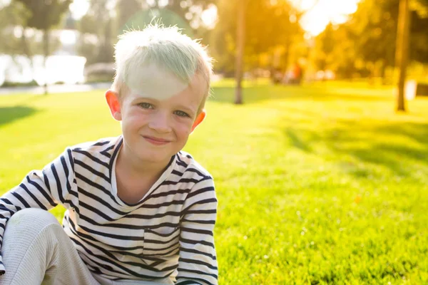 Leuke mooie gelukkig jongetje glimlachend, sit op gras — Stockfoto