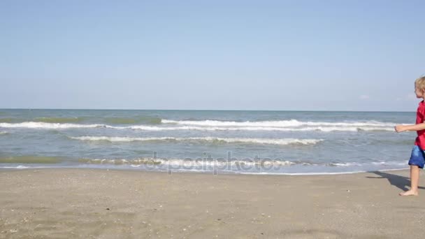 Niño feliz caminando a lo largo de la playa del mar, espacio de copia — Vídeos de Stock