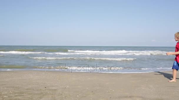 Joyeux petit garçon marchant le long de la plage de la mer, copie-espace — Video