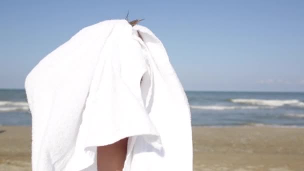 Kleiner glücklich lächelnder feuchter Junge wischt sich nach dem Schwimmen im Meerwasser, wärmt sich am sommerlichen Sandstrand auf — Stockvideo