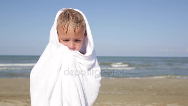 Petit garçon humide mignon qui tremble après avoir nagé dans l'eau de mer, essuie et se réchauffe à la plage de sable d'été — Video