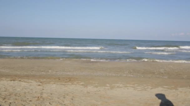 Feliz sonriente niño hermoso caminar a lo largo de la playa del mar en toalla blanca — Vídeo de stock