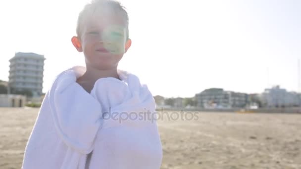 Lyckligt leende liten pojke i vit handduk vid havet stadsstranden skrattar åt kameran — Stockvideo