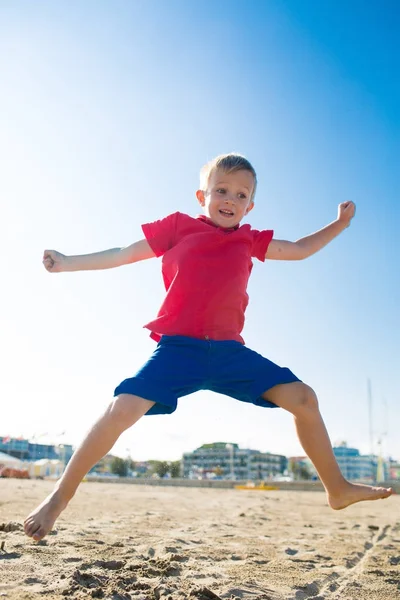 Joyeux beau enfant souriant jouer et sauter à la plage de sable — Photo