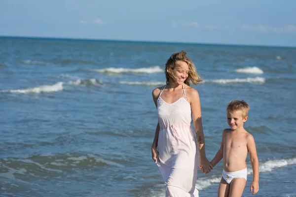 Felice bella giovane mamma e bambino a piedi lungo il mare, copia-spazio — Foto Stock