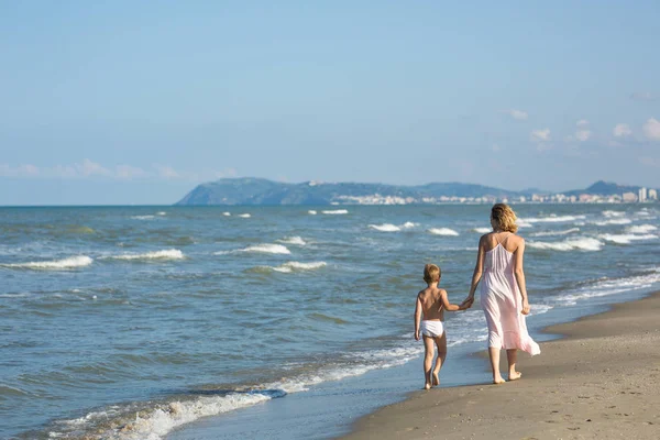 Feliz hermosa mamá y el niño caminan a lo largo de la playa del mar, espacio de copia — Foto de Stock