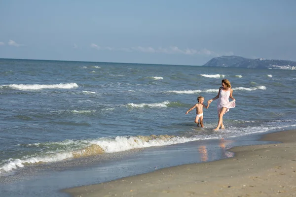 Szczęśliwy, że piękna mama i dziecko ma zabawy w wodzie na plaży Morza — Zdjęcie stockowe