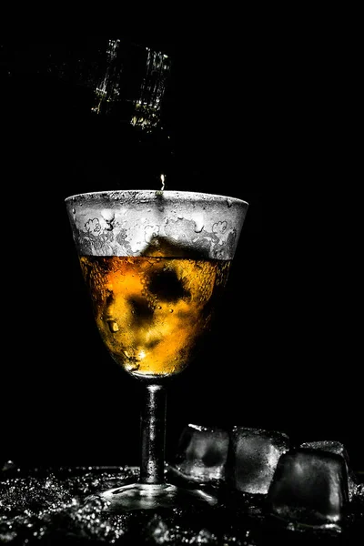 Вкусный напиток, наливаемый в красивое туманное винтажное стекло с кусочками льда — стоковое фото