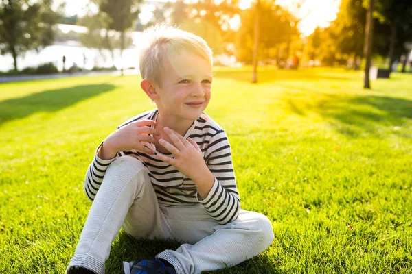 Cute beautiful happy little boy sit on grass enjoying summer time — Stock Photo, Image