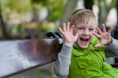 Heyecanlı mutlu küçük sarışın çocuk açık eller yukarı kamera göz ile