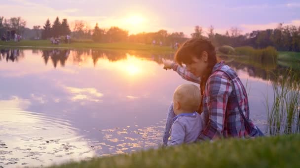 Mãe e filho sentados no banco do lago — Vídeo de Stock