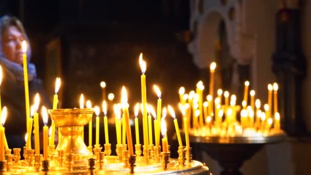 Gebet in der christlichen Kirche. eine Frau steht vor brennenden Kerzen und blickt auf die Ikone eines Gebets — Stockvideo