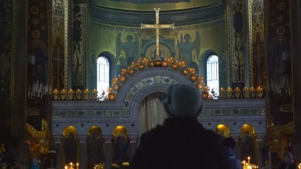 一个女人站在教堂的圣坛前。抬起头看着十字架和圣母玛利亚的寺圆顶上 — 图库视频影像