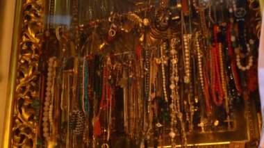 Kutsal kişilerin resmi altında asılı Mücevherat, altın takı, cam bilezik saatler kilise içinde ve taşlar.