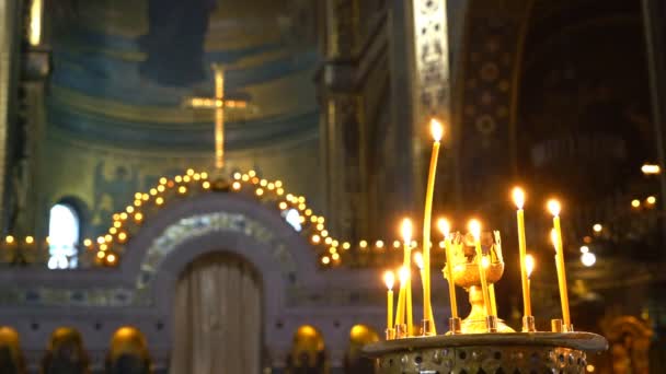 Християнський хрест домінує вхід до вівтаря. Горить свічка і тане віск. — стокове відео