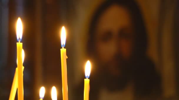 Θέα στην εκκλησία από την καύση κεριά πρόσωπο του Χριστού στο εικονίδιο. Γλείψιμο ιερή φλόγα ανάβει κεριά. — Αρχείο Βίντεο