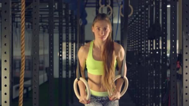 Дівчина в тренажерному залі штовхнув на Кільця гімнастичні. він виконує серія з вправи дивлячись вперед — стокове відео