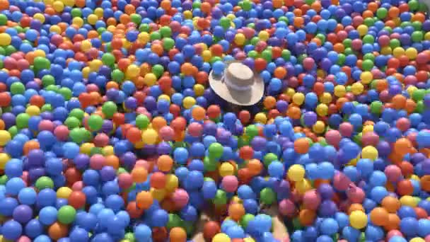 Flickan faller i poolen med färgade bollar. — Stockvideo
