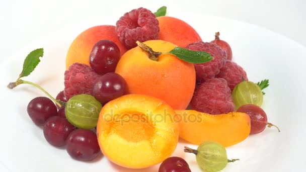 На белом фоне лежат фрукты и ягоды — стоковое видео