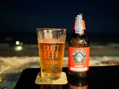 Huahin, Tayland 9 Nisan 2017: Dağ sıçanı Amber şişe bira ve Huahin Beach masada gece süre boyunca Amerikan zanaat bira camına.