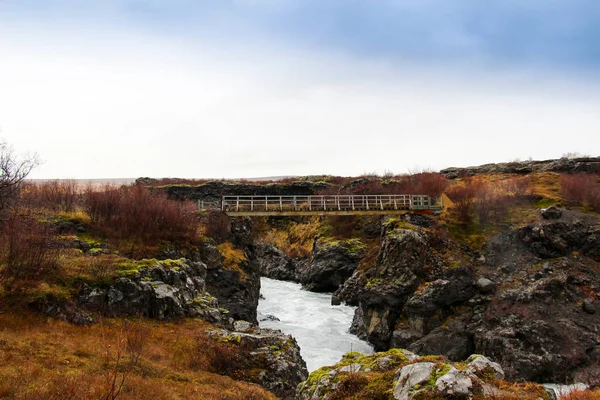 Ocelový most přes vodu potok v hraunfossar, Island. — Stock fotografie