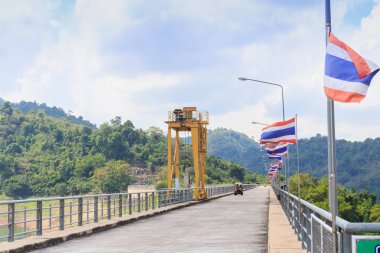 Perspektif Görünümü golf arabası ve Tayland ülke bayrakları ile bir uzun yol Barajı.