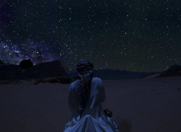 Silhueta de uma pessoa montando o camelo sob as estrelas, Via Láctea e um monte de estrelas sobre a montanha no deserto de Wadi Rum . — Fotografia de Stock