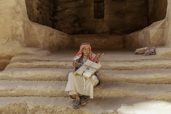 Little Petra, Jordania - 20 de junio de 2017: Viejo beduino u hombre árabe en traje tradicional, tocando su instrumento musical en la puerta de Little Petra . —  Fotos de Stock