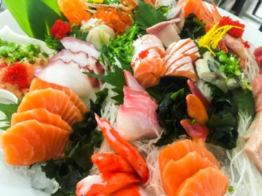 Bir beyaz tabakta yemek çubuğu ile karışık sushi. 