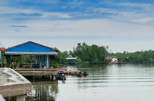 Tayland ortasında uzun kuyruk teknelerle Nehri boyunca evleri.