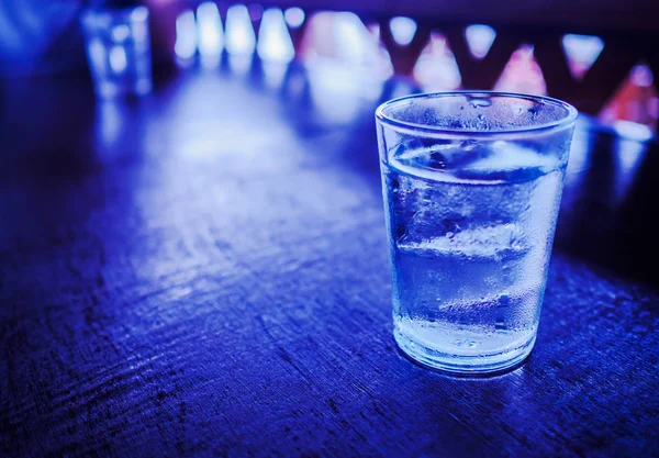 Bir bardak su ile buzda ahşap masa.