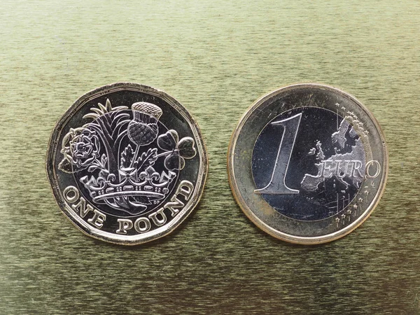 1 libra a 1 euro mince nad kovové pozadí — Stock fotografie