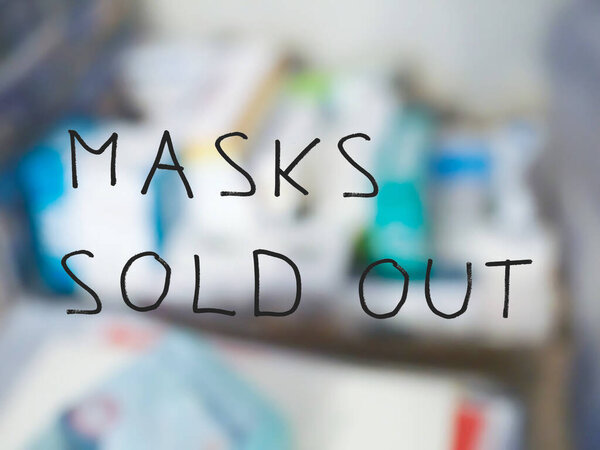 masks sold out sign on pharmacy shop window, with out of focus background of medicines and drugs