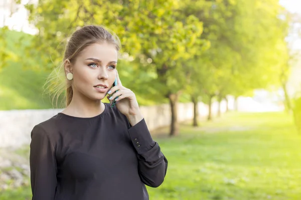 Verleidelijke blonde rechtzetten haar haar en praten over de telefoon op straat in het voorjaar. vrije ruimte voor uw tekst — Stockfoto