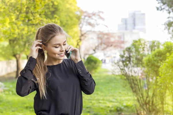 Young blonde woman talking on mobile phone on the street — Stock Photo, Image