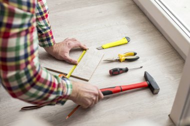 İşçinin laminat koyar. Resimdeki bir adamın elleri ve farklı enstrümanlar