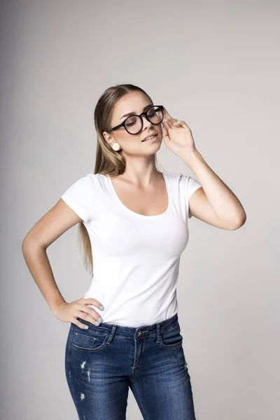 Mujer moderna en camiseta blanca en blanco sobre fondo gris —  Fotos de Stock