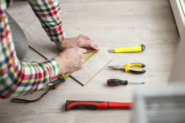 Reparatur, Bau- und Wohnkonzept, Nahaufnahme von Männerhänden auf Parkettboden liegend - Laminatboden. diy — Stockfoto