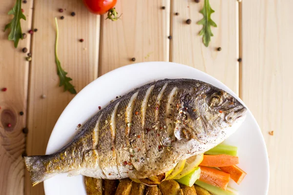 Fried fish dorado with lemon and spices on wood table in a plate Stock Photo