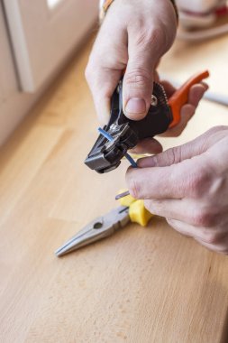 İşçi elektrikçi dairedeki hasarlı prizleri tamir ediyor.